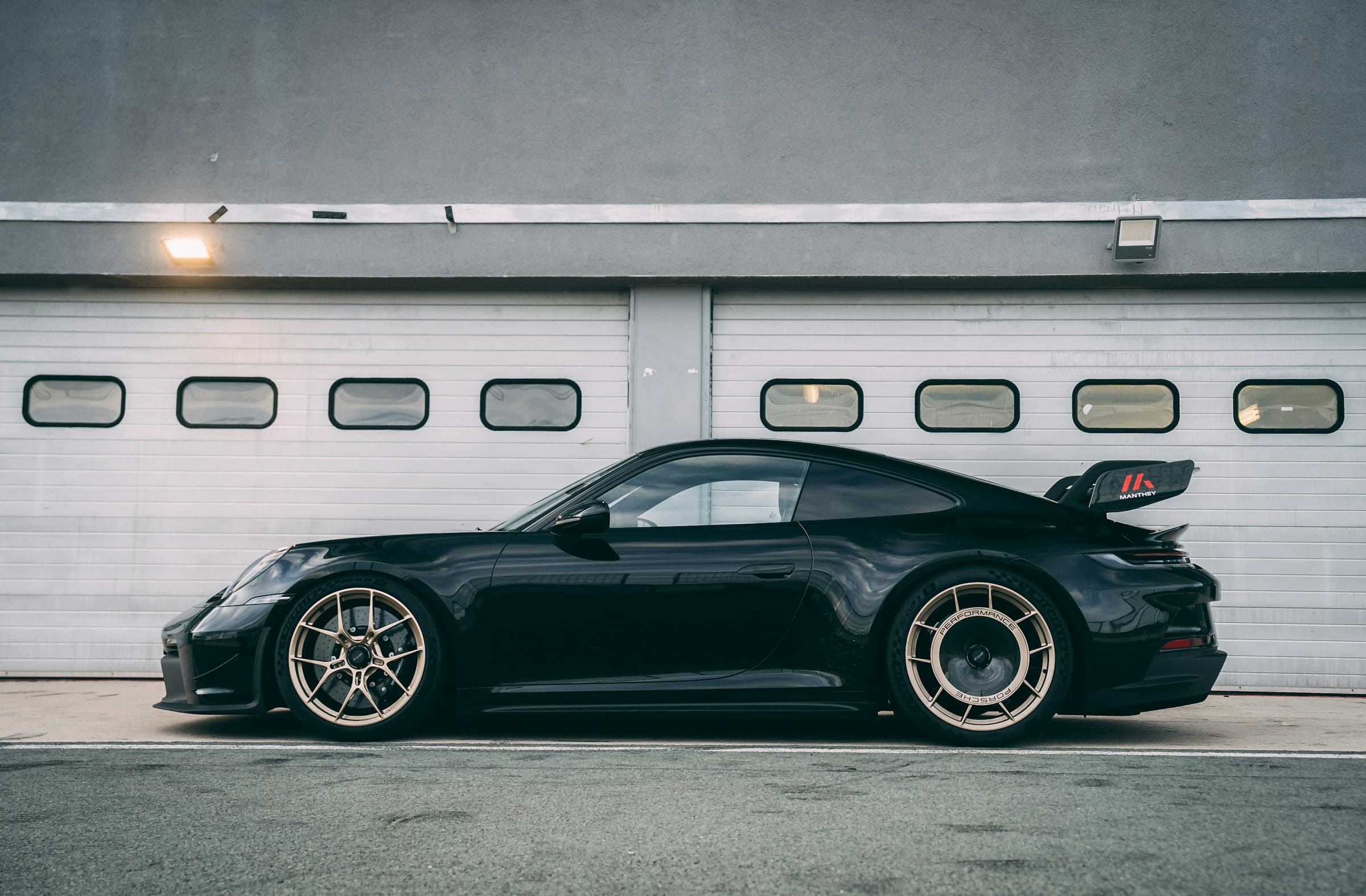 Porsche 911 GT3 noire devant un garage gris
