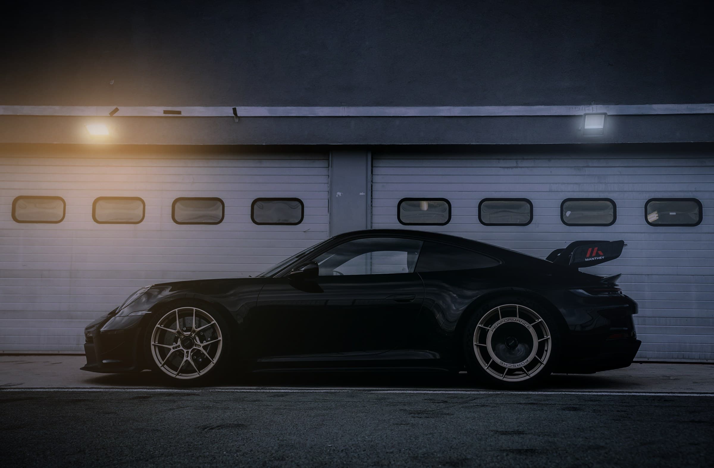 Porsche 911 GT3 noire devant un garage, de nuit